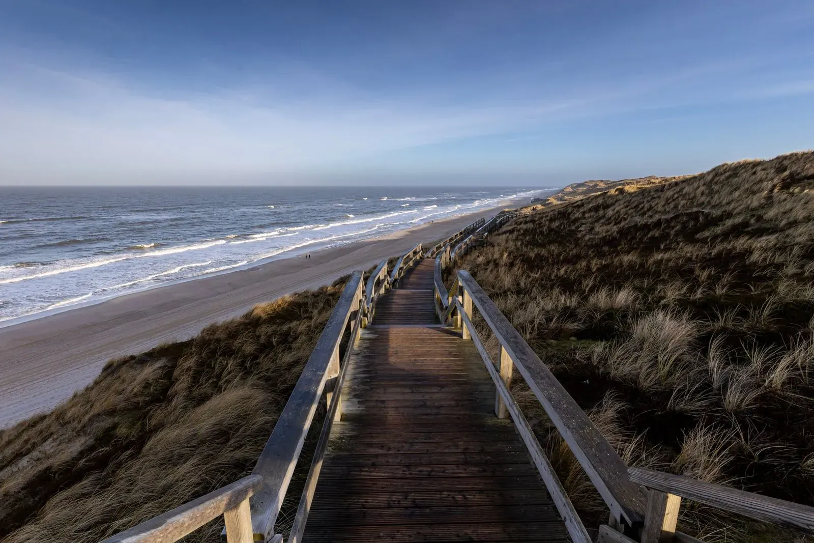 A wooden boardwalk crossing dunes toward the beach