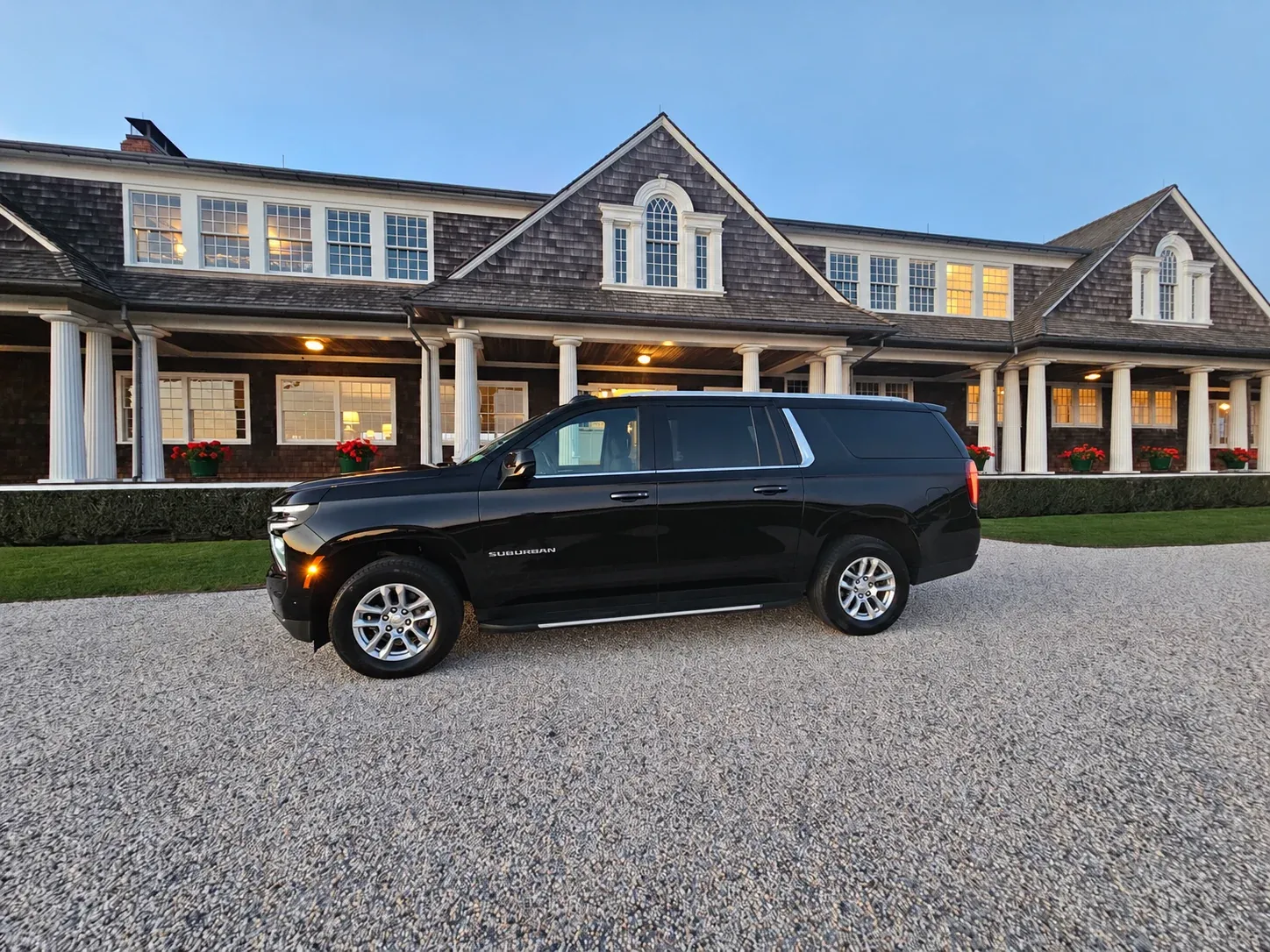 A black East End Lux SUV parked in front of a shingled clubhouse with a long porch