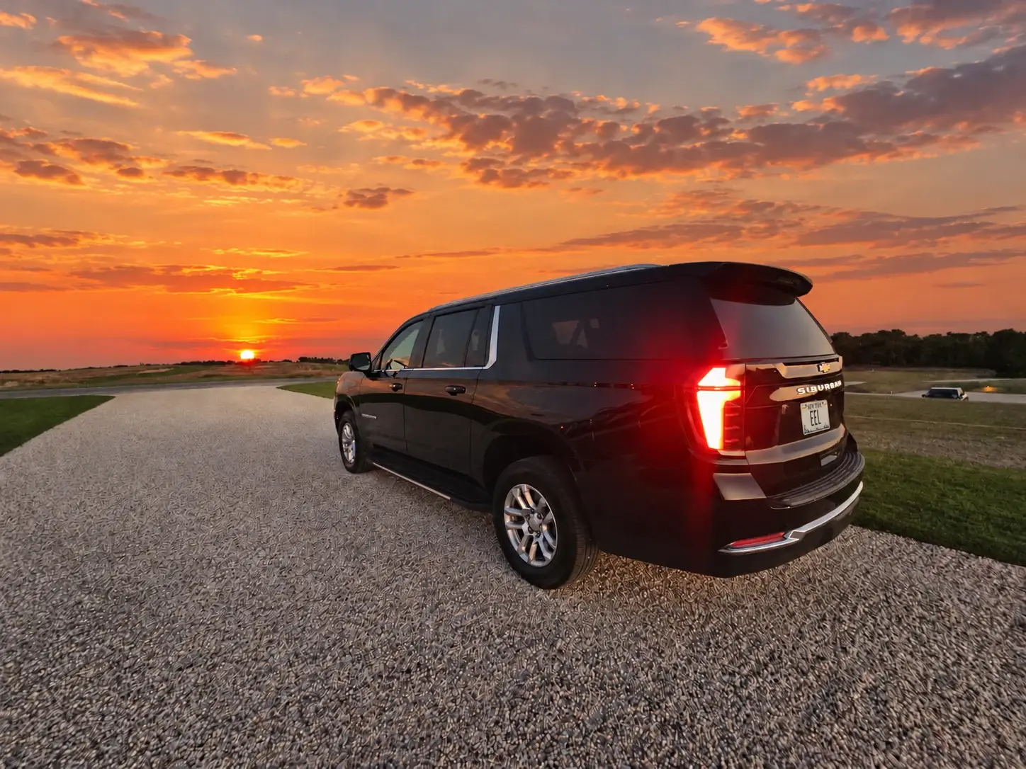 A black East End Lux SUV on an airfield at sunset, seen from behind