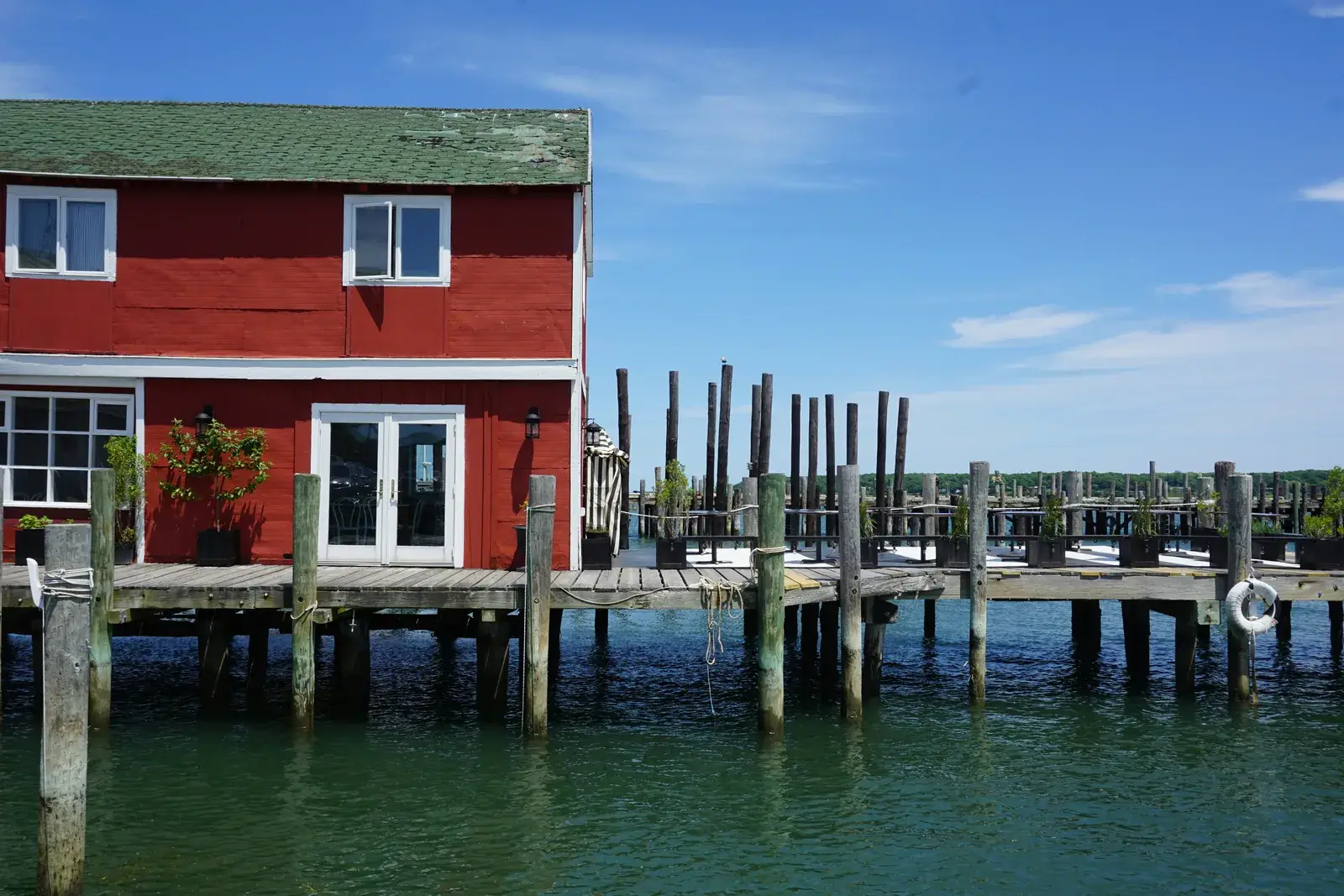A red waterfront building on a wooden pier in Greenport harbor