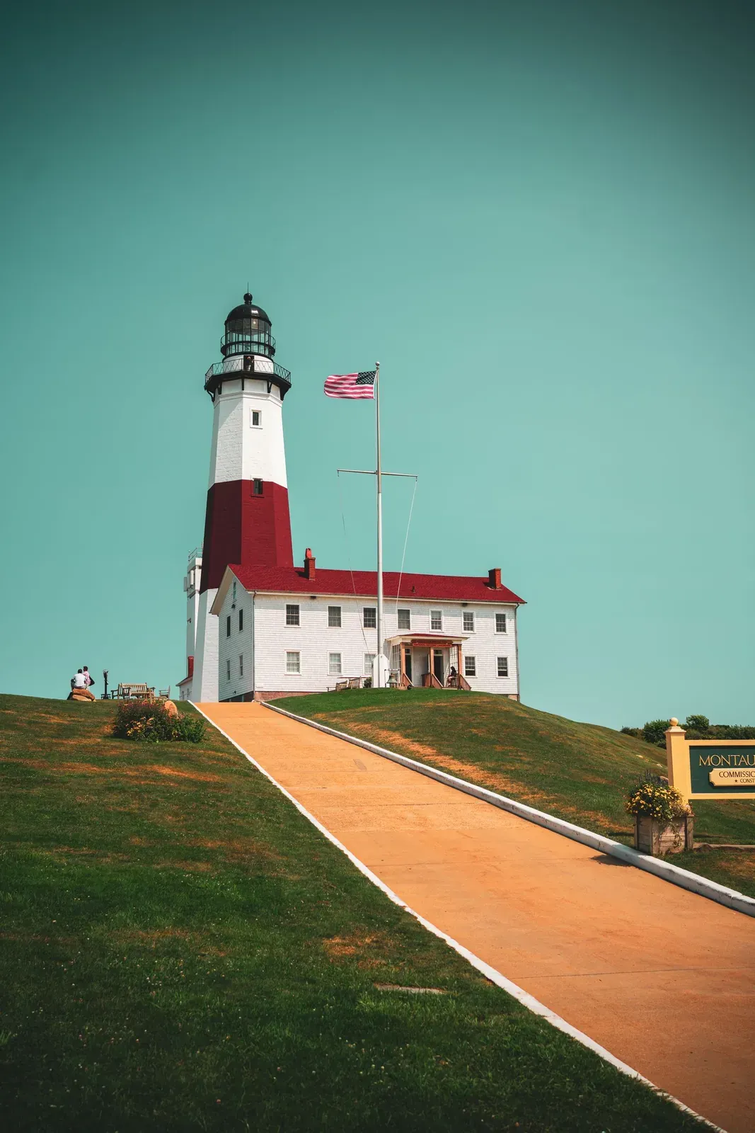 A lighthouse on a green lawn under a clear sky