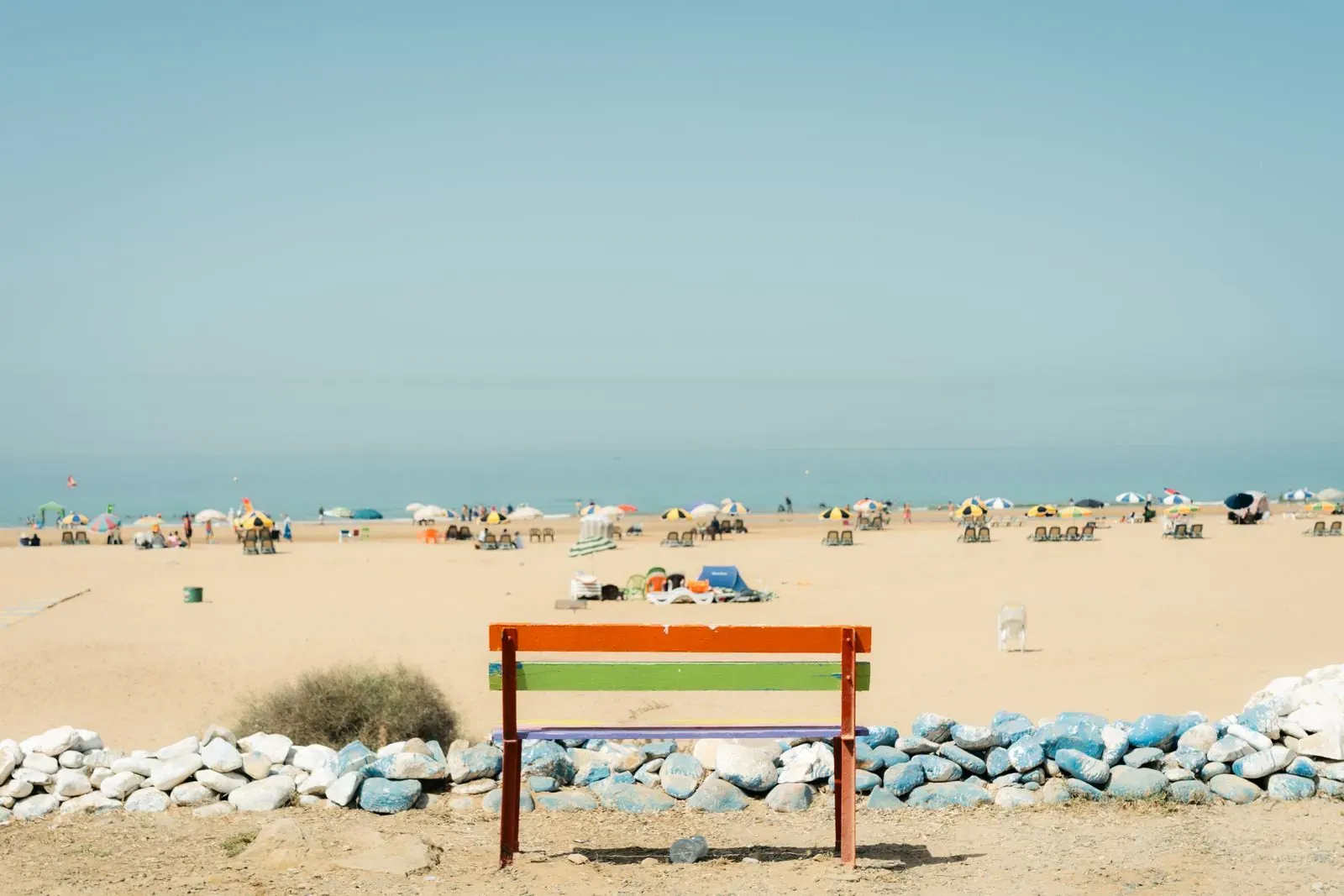 An empty beach with a bench facing the water