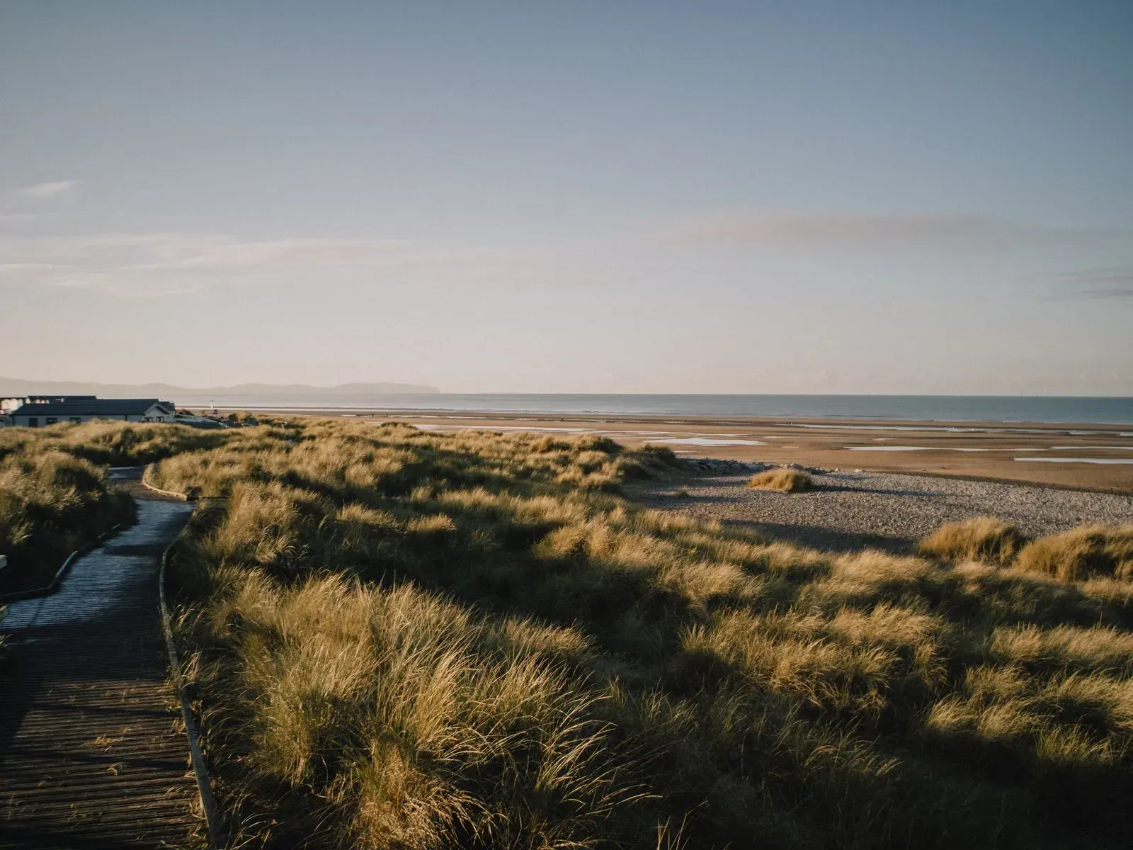 A boardwalk through dunes at sunset